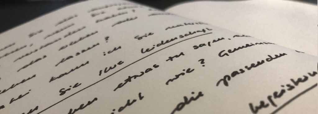 Nahaufnahme einer weißen Notizbuchseite mit handgeschriebenem Text: Auszug aus dem Text auf der Startseite, mit Fokus auf den Wörtern "Leidenschaft" und "begeistern"